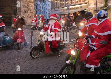 Mitglieder der Vespa-Motorroller-Clubs, die sich während einer Fahrt durch die Stadt Köln als Santas verkleidet haben. Die Roller sind beleuchtet und für Chri dekoriert Stockfoto