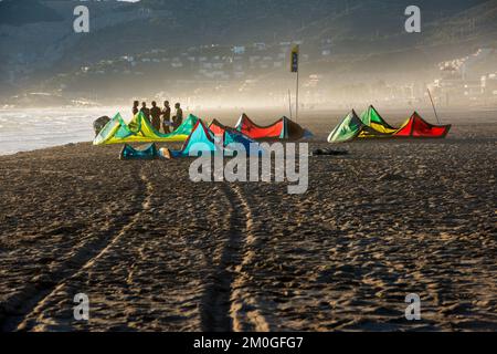 Castelldefels, Barcelona, Spanien - 9. Januar 2016: Eine Gruppe von Kitesurfern mit ihren Drachen wartet am Ufer eines breiten Strandes auf die Windbedingungen Stockfoto