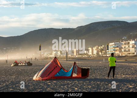 Castelldefels, Barcelona, Spanien - 9. Januar 2016: Junger Mann mit Neopren und Lycra-Hemd wartet neben seinem Drachen am Strand, im Bac Stockfoto