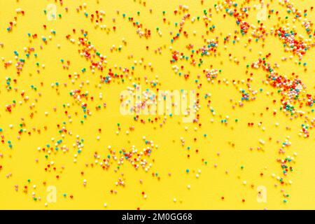 Bunte Süßigkeiten ziehen auf gelbem Hintergrund. Draufsicht. Flaches Lay. Festlich, Geburtstagsfeier, Osterkomposition, Grußkarte. Stockfoto