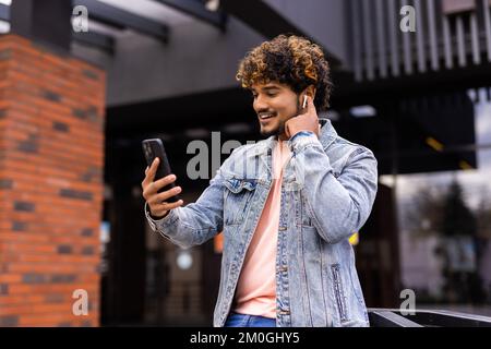 Indischer Geschäftsmann ist entspannend in der Stadt und winken in die Kamera von seinem Telefon in einer Videokonferenz Stockfoto