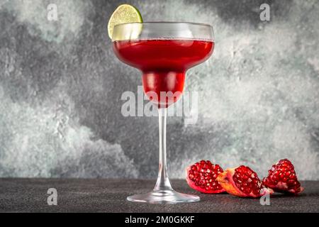 Ein Glas Granatapfel-Margarita-Cocktail auf grauem Hintergrund Stockfoto