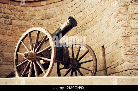 Eine antike Kanone aus nächster Nähe vor dem Hintergrund der Festungsmauer der Altstadt. Baku. Republik Aserbaidschan, getönt Stockfoto
