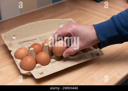 Lancashire Vereinigtes Königreich. Aufgenommen am 6. Dezember 2022. Ein Mann, der ein Ei aus einem Karton mit einem Dutzend Aldi-Supermarkt-Eiern nimmt Stockfoto