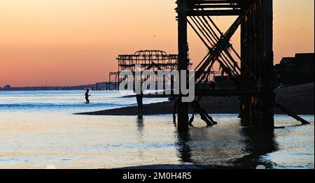 Brighton UK 6. . Dezember 2022 - Schwimmer genießen einen herrlich kühlen Sonnenuntergang am Brighton Beach , da Großbritannien in den nächsten Tagen von einer kalten Wetterwelle heimgesucht wird . : Credit Simon Dack / Alamy Live News Stockfoto