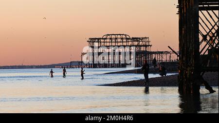 Brighton UK 6. . Dezember 2022 - Schwimmer genießen einen herrlich kühlen Sonnenuntergang am Brighton Beach , da Großbritannien in den nächsten Tagen von einer kalten Wetterwelle heimgesucht wird . : Credit Simon Dack / Alamy Live News Stockfoto