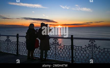 Brighton UK 6. . Dezember 2022 - Besucher beobachten den wunderschönen Sonnenuntergang in Brighton in der Dämmerung , während Großbritannien in den nächsten Tagen von einer kalten Witterung heimgesucht wird . : Credit Simon Dack / Alamy Live News Stockfoto