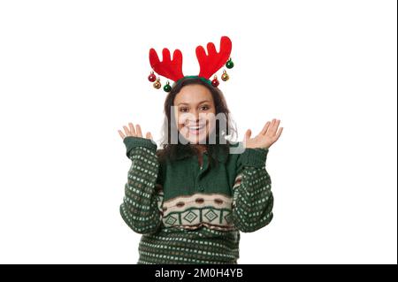 Eine charmante Frau, die ein Hirschgeweih trägt, positive Emotionen ausdrückt, auf weißem Hintergrund posiert und freie Werbefläche hat Stockfoto