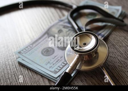 Stethoskop und Geld auf Holztisch. Gesundheitswesen, Behandlungskosten und Medizinkonzept. Stockfoto