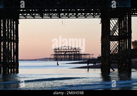 Brighton UK 6. . Dezember 2022 - Schwimmer genießen einen herrlich kühlen Sonnenuntergang am Brighton Beach , da Großbritannien in den nächsten Tagen von einer kalten Wetterwelle heimgesucht wird . : Credit Simon Dack / Alamy Live News Stockfoto