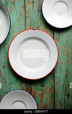 Weiß lackierte Metallplatten auf einem grünen Holztisch. Stockfoto