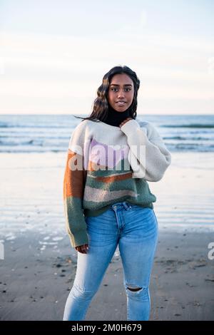 Junge Indianerin, die am Strand spaziert und in die Kamera schaut Stockfoto