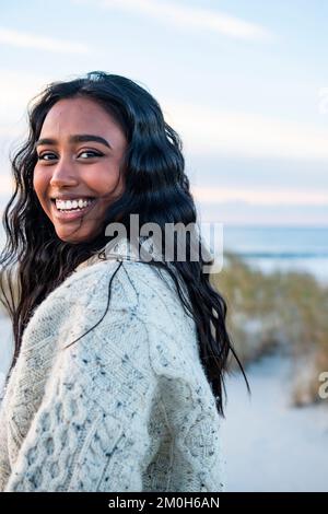 Lächelndes Porträt einer jungen Indianerin am Strand, die in die Kamera schaut Stockfoto