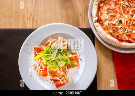 Zenithaler Schuss von leckeren Ravioli mit Tomatensoße mit Rucola an Stockfoto