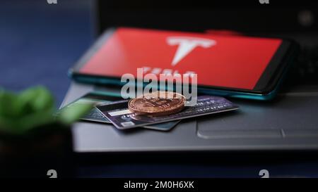 Dobrich, Bulgarien – 2022. November 26: Mobiltelefon auf einem Laptop mit Tesla Logo, Bitcoin und Kreditkarten. Anschauliches Editorial-Konzept Stockfoto