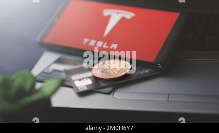 Dobrich, Bulgarien – 2022. November 26: Mobiltelefon auf einem Laptop mit Tesla Logo, Bitcoin und Kreditkarten. Anschauliches Editorial-Konzept Stockfoto