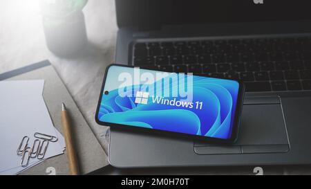 Dobrich, Bulgarien – 2022, November 26: Mobiltelefon auf einem Laptop mit dem Microsoft-Logo und Windows 11. Anschauliches Editorial-Konzept für Software Stockfoto