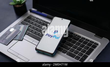 Dobrich, Bulgarien – 2022, November 26: Mobiltelefon auf einem Laptop mit PayPal-Logo und Kreditkarten im Hintergrund. Zur Veranschaulichung Stockfoto