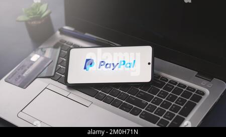 Dobrich, Bulgarien – 2022, November 26: Mobiltelefon auf einem Laptop mit PayPal-Logo und Kreditkarten im Hintergrund. Zur Veranschaulichung Stockfoto