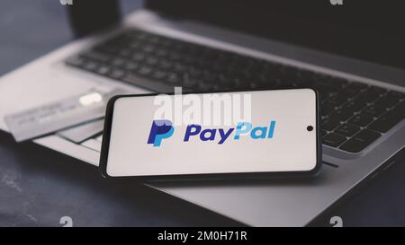 Dobrich, Bulgarien – 2022, November 26: Mobiltelefon auf einem Laptop mit PayPal-Logo und Kreditkarten im Hintergrund. Zur Veranschaulichung Stockfoto