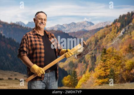 Der Holzfäller lächelt und hält eine Axt im Wald Stockfoto