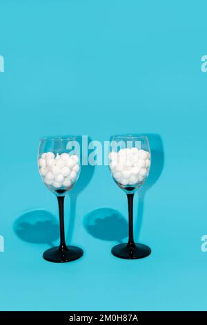 Weingläser mit weißen Blasen auf blauem Hintergrund. Minimale Partyzusammensetzung. Stockfoto