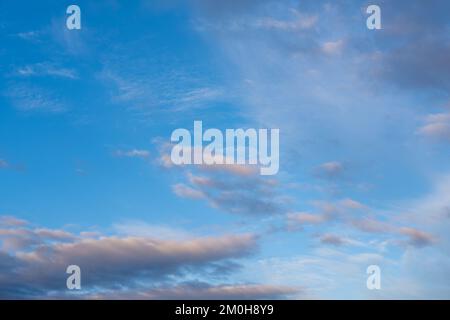 Wunderschöner Sonnenuntergang- oder Sonnenaufgangshimmel, der dunkelblaue und blassrosa Wolken erhellt. Wolkiger Himmel, um auf Ihren Fotos zu überlagern. Stockfoto