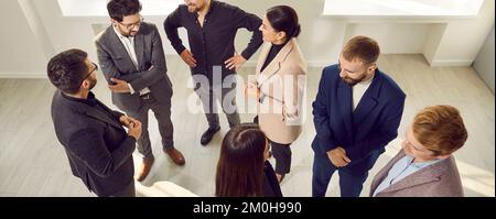 Gruppe positiver Geschäftsleute im Büro, die ein entspanntes Gespräch über ein neues Projekt führen. Stockfoto