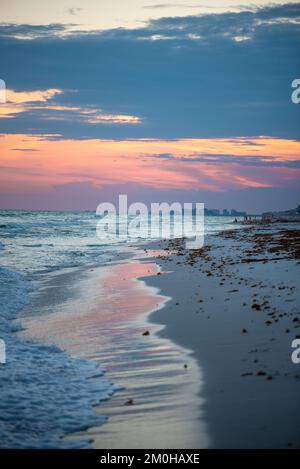 Eine vertikale Aufnahme eines faszinierenden, ruhigen Sonnenuntergangs über dem Strand Stockfoto