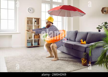 Der lustige, fette Mann bleibt während der Sommerferien zu Hause, gibt aber vor, am Strand im Meer zu tauchen Stockfoto