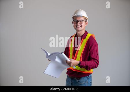 Das lächelnde Gesicht des Ingenieurs, der einen Bauplan in der Hand hält Stockfoto