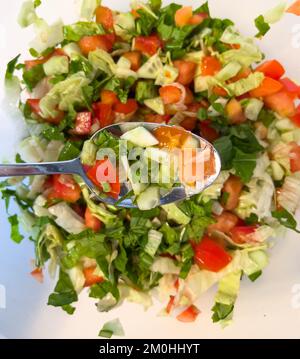 Blick von oben auf den Salat im Löffel. Türkischer Schäfersalat. Nahaufnahme gewürfelter Salat. Stockfoto