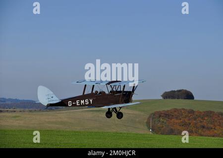 Ein De Havilland Tiger Moth Doppeldecker, der vom Flugplatz Compton Abbas in den wunderschönen, klaren blauen Himmel abhebt. In der Nähe von Shaftesbury in Dorset. Stockfoto