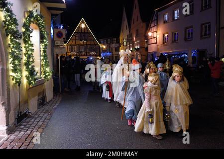 Frankreich, Haut Rhin, Eguisheim, der Christkindel mit seiner Krone aus Kerzen und die Engel begleiten die vielen Kinder, die ihre Laternen für die Lichterprozession in den Gassen der Stadt halten, sie ehrt die Heilige Lucia, eine der traditionellen Charaktere der elsässischen Weihnachten Stockfoto