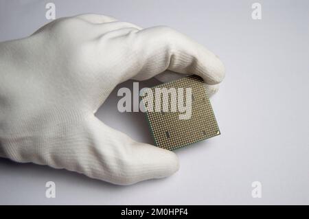 Bild eines CPU-Chips in der Hand, CPU mit vielen Pins, auf weißem Hintergrund. Stockfoto