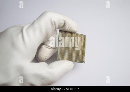 Bild eines CPU-Chips in der Hand, CPU mit vielen Pins, auf weißem Hintergrund. Stockfoto