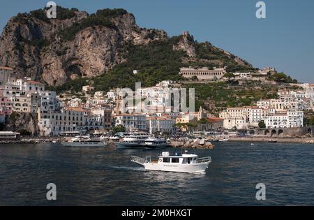 Allgemeiner Blick auf die Stadt Amalfi vom Yachthafen aus mit Blick auf die Stadt mit Battellieri Amalfi im Vordergrund und malerischen Klippen im Hintergrund. Stockfoto