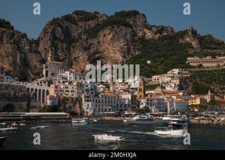 Allgemeiner Blick auf Amalfi Stadt vom Yachthafen aus mit Blick auf die Hauptstadt mit Vergnügungsbooten im Vordergrund und malerischen Klippen im Hintergrund. Stockfoto