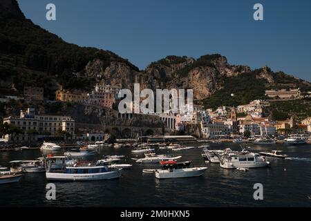 Ein allgemeiner Blick auf Amalfi Stadt von der Marina Mauer über den Hafen und die Hauptstadt mit Booten im Vordergrund und Kalksteinklippen im Hintergrund. Stockfoto