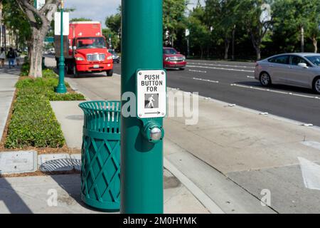 Anaheim, CA, USA – 1. November 2022: Ein Druckknopf für einen Fußgängerüberweg auf einem grünen Pfosten in einer Stadtstraße in Anaheim, Kalifornien. Stockfoto