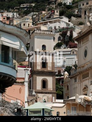 Der Glockenturm der Kirche Santa Maria Assunta hebt sich vor dem Hintergrund vertikaler Schichten von Häusern in Positano Italien hervor. Stockfoto