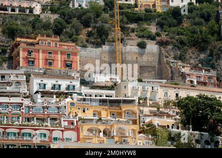 Die farbenfrohen Häuser, Geschäfte und Hotels von Positano schichten vertikal auf den Klippen mit Blick auf den Yachthafen grande Beach Italien. Das Bild zeigt den Kran in Schießerei. Stockfoto