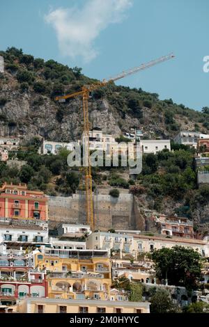 Die farbenfrohen Häuser, Geschäfte und Hotels von Positano schichten vertikal auf den Klippen mit Blick auf den Yachthafen grande Beach Italien. Das Bild zeigt den Kran in Schießerei. Stockfoto