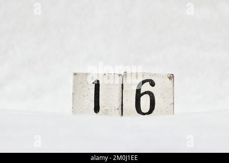 Nummer 16 Kalender aus altem Holzblock auf weißem Schneehintergrund, Platz für Text. Merken Sie sich das Datum für Geburtstag, Jubiläum, besonderen Tag oder Anlass Stockfoto