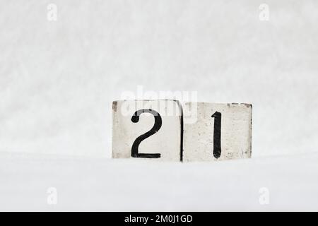 21 Kalendernummer aus altem Holzblock auf weißem Schneehintergrund, Kopierbereich für Text. Merken Sie sich das Datum für Geburtstag, Jubiläum, besonderen Tag oder Anlass Stockfoto