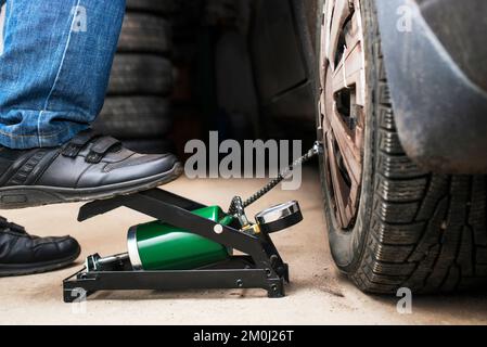 Der Fuß eines Mannes pumpt einen Platten Autoreifen oder Reifen hoch, der leer ist Stockfoto