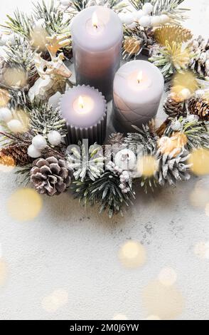 Dekorierter Adventskranz aus Tannenzweigen mit brennenden Kerzen, Tradition in der Zeit vor Weihnachten. Weißer, alter Holzhintergrund. Stockfoto