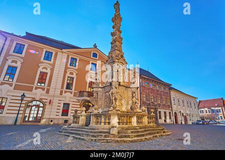 Die mittelalterliche Pestsäule (Morovy Sloup) in der Sultysova-Straße mit historischen Gebäuden und einem im Hintergrund mit Fresken geschmückten Stadthaus, Kutna Hora, Tschechische Republik Stockfoto