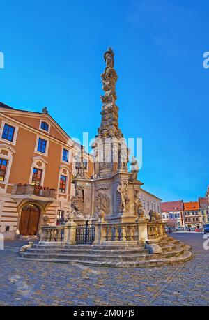 Die mittelalterliche Pestsäule in der Sultysova-Straße mit historischen Häusern im Hintergrund, Kutna Hora, Tschechische Republik Stockfoto