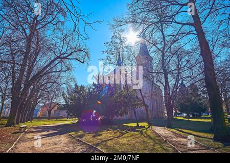 Der sonnige Frühlingspark mit der Silhouette der Jakobskirche hinter den Bäumen, Kutna Hora, Tschechische Republik Stockfoto